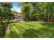 Large backyard with a deck, seating area and lush green lawn surrounded by trees and fencing at 2213 Normandin Ct, Charlotte, NC 28216