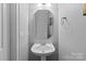 Cozy powder room with pedestal sink, modern mirror, and neutral color scheme at 2213 Normandin Ct, Charlotte, NC 28216