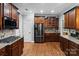 Chef's kitchen with dark wood cabinets, stainless steel appliances, and granite countertops at 2213 Normandin Ct, Charlotte, NC 28216