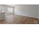 Open-concept living room with hardwood floors, neutral paint, and natural light from kitchen windows at 2720 Lehigh Rd, Charlotte, NC 28208