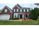 Stunning two-story brick home featuring a manicured lawn, mature trees, and classic architectural design at 2763 Rivendale Ct, Indian Land, SC 29707