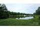 A tranquil pond with a fountain, surrounded by lush greenery and mature trees, creates a serene outdoor setting at 2763 Rivendale Ct, Indian Land, SC 29707