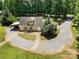 Aerial view of a charming home with a circular driveway, mature trees, and lush landscaping in a serene setting at 2845 Lakefront Dr, Belmont, NC 28012