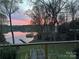 Captivating view of the lake with a colorful sunset, surrounded by lush trees at 2845 Lakefront Dr, Belmont, NC 28012