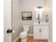 Small powder room featuring wood floors, white cabinets, black hardware, and an oval mirror at 2845 Lakefront Dr, Belmont, NC 28012