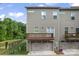 Modern townhome featuring a two-car garage, balcony, and neutral siding, set against a backdrop of lush trees at 3003 Salix Bend Dr, Charlotte, NC 28205