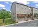 A corner view of a modern townhome shows a two-car garage, balcony, and well-maintained lawn on a sunny day at 3003 Salix Bend Dr, Charlotte, NC 28205