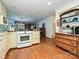 Open kitchen with wood floors, white appliances, shelving, and open flow into other living spaces at 4951 Dayspring Dr, Mint Hill, NC 28227