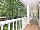 Covered porch featuring stone-look floor, white railing, and serene wooded views at 4951 Dayspring Dr, Mint Hill, NC 28227