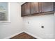 The laundry room features wood floors, neutral paint, base trim, a window, and storage cabinets at 5183 Mill Race Ln, Lancaster, SC 29720