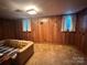 Cozy basement with wood paneled walls, carpeted floor, and a comfortable sofa at 5495 Valley Run St, Hickory, NC 28601