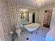 A cozy bathroom featuring a vintage-style tub, a large mirror, and yellow floral wallpaper at 5495 Valley Run St, Hickory, NC 28601