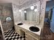 Bathroom with black and white checkered floors, newspaper-themed wallpaper, and double sink vanity at 5495 Valley Run St, Hickory, NC 28601
