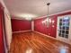 Spacious living room featuring hardwood floors, decorative chandeliers and painted red walls at 5495 Valley Run St, Hickory, NC 28601