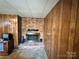 Living room featuring wood paneling, a brick fireplace, and a plush neutral carpet at 5495 Valley Run St, Hickory, NC 28601