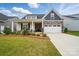 Charming home showcasing a well-manicured lawn, lovely landscaping, a two-car garage and stone and traditional siding at 5723 Notch Peak Ave, Indian Land, SC 29707