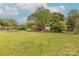 Spacious backyard with ample green space, mature trees, fire pit, and a glimpse of the home's exterior at 6024 Highview Rd, Weddington, NC 28104