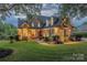 Beautiful brick home at dusk showcases manicured lawn, warm exterior lighting, and inviting curb appeal at 6024 Highview Rd, Weddington, NC 28104