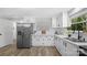 Well lit kitchen with white cabinets, stainless steel fridge, hardwood floors, and a window above the sink at 7860 Henry Harris Rd, Fort Mill, SC 29707