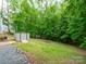 A spacious backyard featuring mature trees, a storage shed, and a small gravel area at 8905 Vagabond Rd, Mint Hill, NC 28227