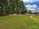 Fenced backyard with mature trees and lawn, features a walkway and shed for extra storage at 1040 Spring Dr, Gastonia, NC 28052
