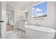 Bathroom with white marble floors, white cabinets, and a freestanding tub at 13618 Tranquil Day Dr, Matthews, NC 28105