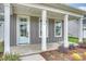 Inviting front porch with white columns, gray siding, and neatly landscaped flower beds at 13618 Tranquil Day Dr, Matthews, NC 28105