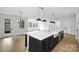 Bright open kitchen with black island, white marble countertop, apron sink, and stainless steel appliances at 13618 Tranquil Day Dr, Matthews, NC 28105