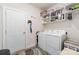 Clean laundry room with white washer and dryer, overhead shelving, and a white door at 160 Tanner Loop, Troutman, NC 28166