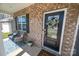 Inviting front porch featuring brick, seating, and a decorative wreath on the stylish black front door at 17228 River Race Dr, Huntersville, NC 28078