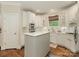 Cozy kitchen featuring white cabinets, a tile backsplash, stainless steel appliances, and an island with a white countertop at 1814 Therrell Farms Rd, Waxhaw, NC 28173