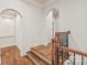 Elegant hallway showcasing a staircase with decorative iron railings, wood floors, and arched doorways at 18843 Flat Shoals Dr, Cornelius, NC 28031