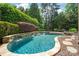 Picturesque pool area with rock accents and a gentle waterfall, surrounded by vibrant greenery for a serene retreat at 18843 Flat Shoals Dr, Cornelius, NC 28031