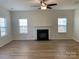 Spacious living room features a ceiling fan, a fireplace, and two large windows at 2018 Rockycreek Ln, Monroe, NC 28112