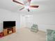 Open living area with neutral carpet, a fan, and a TV, creating a welcoming and functional space at 2306 Nettleton Ct, Matthews, NC 28105