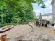 A large stone patio has a stone fire pit, dining table with umbrella, and is surrounded by mature trees at 2306 Nettleton Ct, Matthews, NC 28105