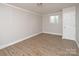 Bright bedroom features neutral walls, trim and wood grain flooring, with one window and a door at 2409 Thornton Rd, Charlotte, NC 28208