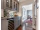 Butler's pantry with gray cabinetry, mirrored backsplash, wine cooler, and view into dining room at 2410 Vernon Dr, Charlotte, NC 28211