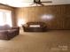 Spacious living room with a ceiling fan, paneled walls and a large carpeted area for furniture arrangement at 2583 Robinson Rd, Newton, NC 28658