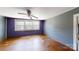 A purple bedroom with three windows, wood floors, and a ceiling fan at 2645 Kool Park Ne Rd, Hickory, NC 28601