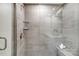 Close-up of the glass-enclosed walk-in shower with gray tile, a shower bench, and glass shelving at 3844 Cheyney Park Dr, Charlotte, NC 28269