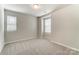 Bright bedroom featuring neutral carpet, two windows with blinds, and a modern ceiling light at 3936 Cheyney Park Dr, Charlotte, NC 28269