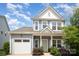 Charming two-story home with a light blue exterior, inviting front porch, and attached garage with white door at 40154 Crooked Stick Dr, Lancaster, SC 29720