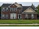 Charming two-story brick home featuring blue shutters, a well-manicured lawn, and a classic architectural design at 6017 Lowergate Dr, Waxhaw, NC 28173