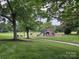 Community playground featuring a slide and play structure in a lush green space with mature trees and benches at 6017 Lowergate Dr, Waxhaw, NC 28173