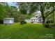 Large green backyard featuring two sheds, a patio with a fire pit, and mature trees at 6512 Porterfield Rd, Charlotte, NC 28226