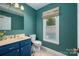 Colorful bathroom featuring a blue vanity and natural light at 6512 Porterfield Rd, Charlotte, NC 28226