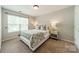Bright bedroom with neutral carpet, large window, stylish headboard, and bedside tables at 6917 Rothchild Dr, Charlotte, NC 28270