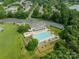 Aerial view of a community clubhouse with a pool and lounge area surrounded by green lawns and parking at 6917 Rothchild Dr, Charlotte, NC 28270