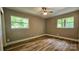 This bedroom features hardwood floors, neutral paint, two windows, and a ceiling fan with light at 7021 Linda Lake Dr, Charlotte, NC 28215